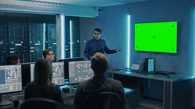 专业IT开发团队开会，演讲者谈论新概念，墙上电视有绿色模拟屏幕。概念:软件开发，深度学习，人工智能，数据挖掘视频素材