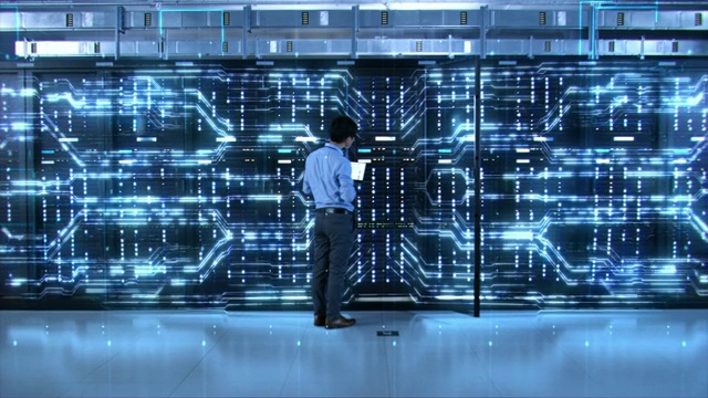IT专家站在服务器机架前，带着笔记本电脑，用触摸手势激活数据中心。缩小视频素材