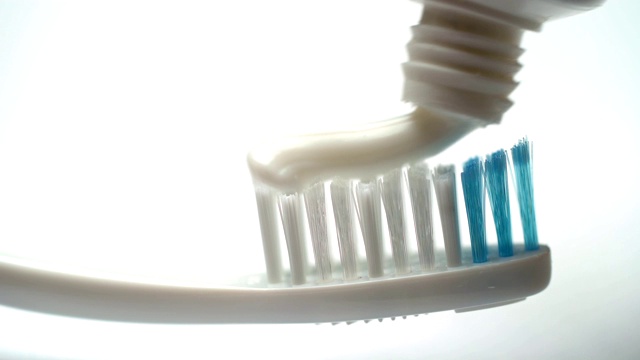 将牙膏贴在牙刷上，涂在白色的背景上，清洁牙齿，卫生视频下载