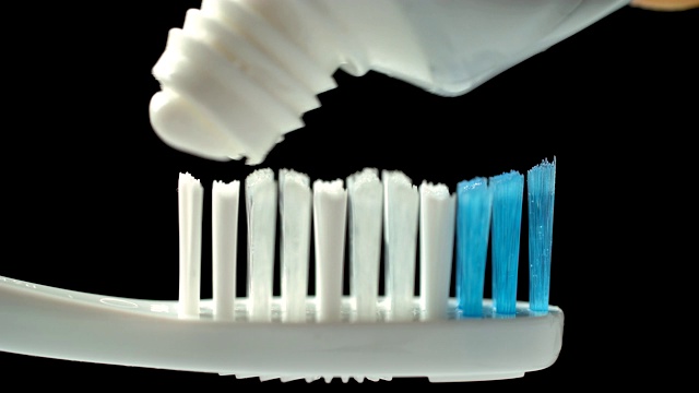 把牙膏放在牙刷上，涂在黑色的背景上，卫生，清洁牙齿视频下载