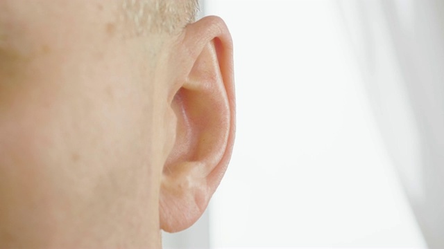 成年男性的耳朵靠近。男人在动他的耳朵。耳鼻喉科和听力健康视频下载