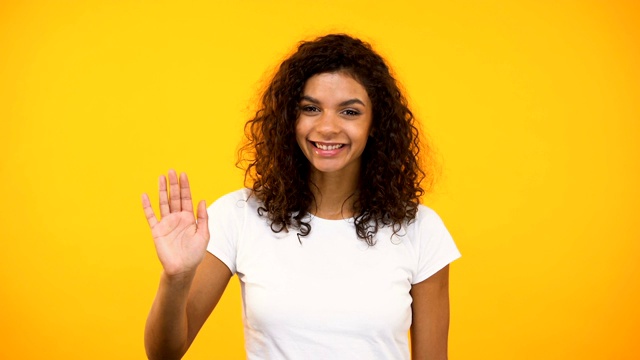 友好的非裔美国女孩挥手向镜头问好，欢迎视频下载