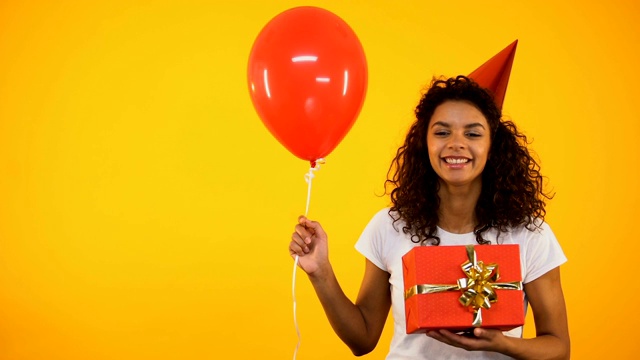 快乐的混血女孩拿着礼物盒和气球，庆祝生日派对视频下载