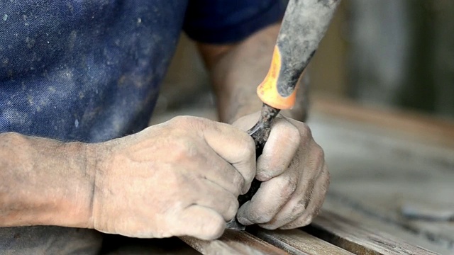 在工作中，他是一个专业的木匠，他是用木工工具雕刻木头，双手靠近，木工和工艺的概念视频下载