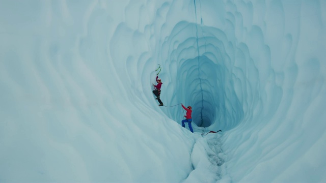保护员协助冰攀登者使用钩子攀登冰川隧道/美国阿拉斯加帕尔默视频素材