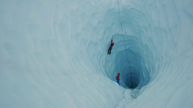 保护员协助冰攀登者攀登冰川隧道/美国阿拉斯加帕尔默视频素材