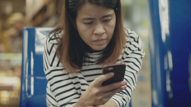一名亚洲女性在机场使用智能手机视频素材