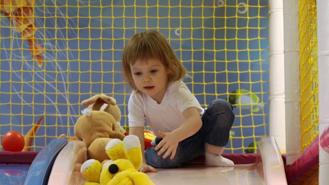 小女孩坐在儿童滑梯上滚动毛绒玩具视频下载