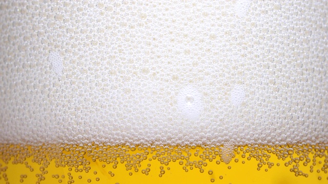 将冰镇啤酒倒入有水滴的玻璃杯中视频素材