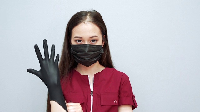 严肃的女人戴着防护面具戴着黑色手套在灰色的背景视频素材