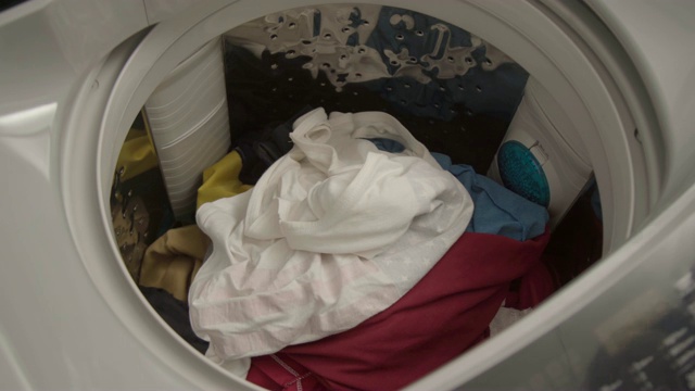 洗衣机内的手拿衣服的特写。视频素材