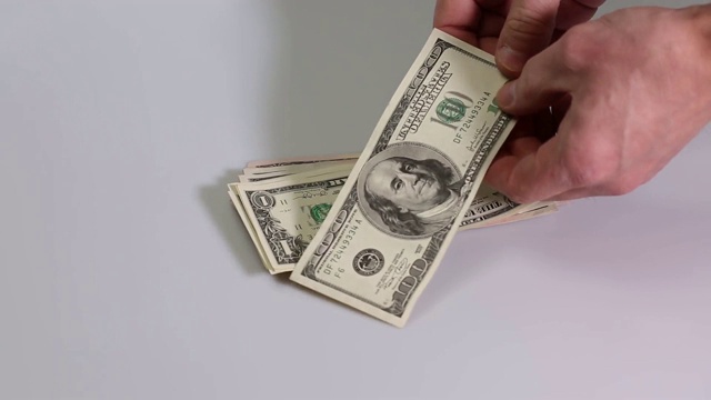 短片显示一个男人检查一堆美元钞票。美元的钞票。金融背景。视频素材