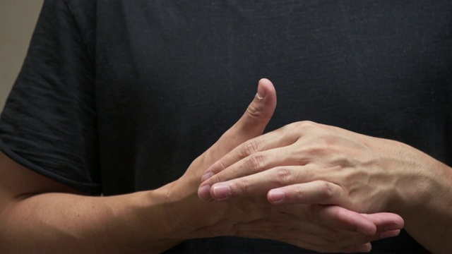 穿着黑色衬衫的亚洲人感到手指疼痛。肌肉疼痛，保健理念。视频下载
