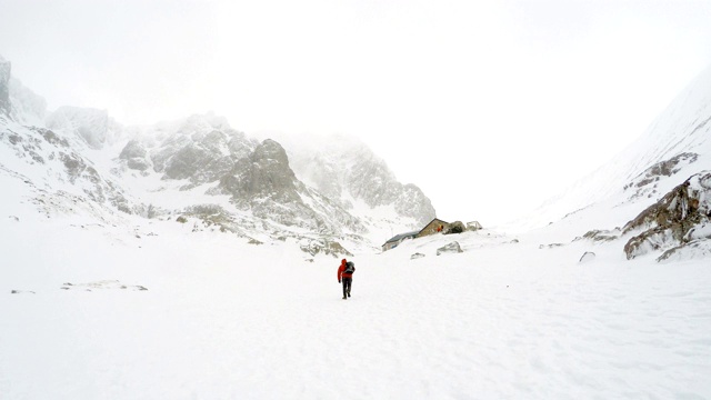 背着背包的旅行者在雪山上行走视频素材