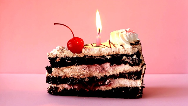 粉红色背景上的樱桃和燃烧的蜡烛的纸杯蛋糕。时间流逝的视频视频素材