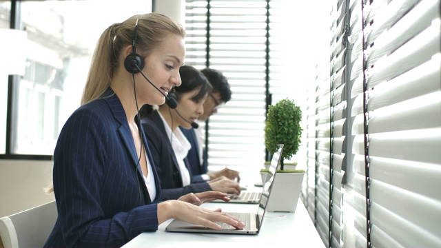 呼叫中心的女商人和团队使用耳机为客户提供支持，并陪同呼叫中心的团队视频素材