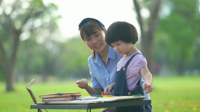 亚洲小女孩在花园与年轻的老师学习视频素材