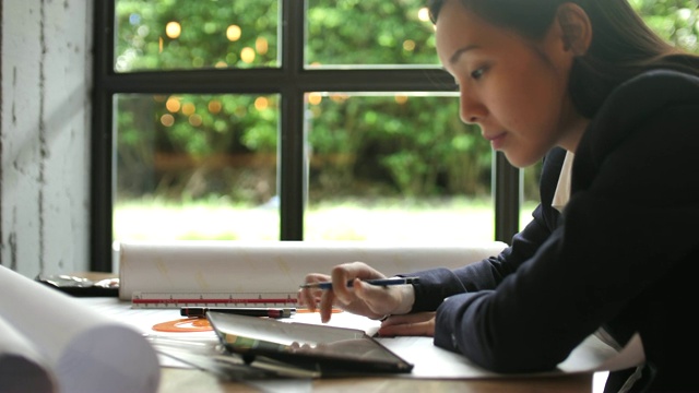 年轻的亚洲女建筑师在桌子上画画视频下载