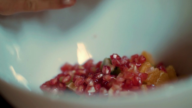 女人把石榴放在水果沙拉的碗里视频素材