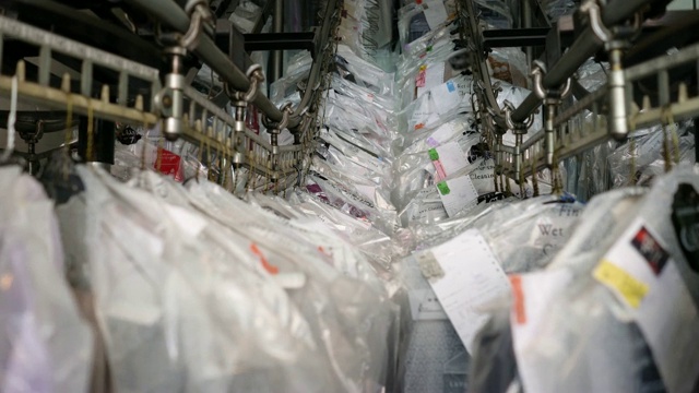 近距离的清洁衣服挂在传送带在一个工业洗衣服务视频素材