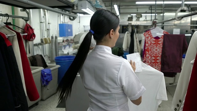 在工业洗衣服务中把衣服从一个架子移到另一个架子上的妇女视频素材