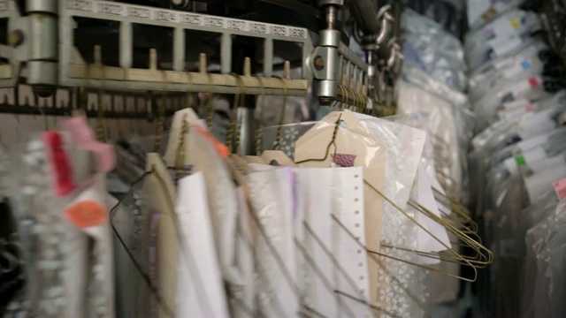 近距离的工业传送带在一个工业洗衣服务与衣服挂在上面视频素材