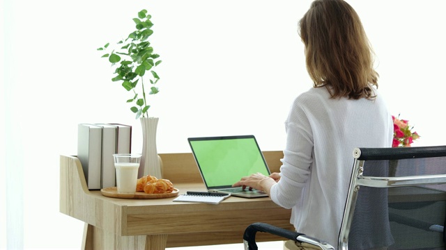 女人看着绿色屏幕的笔记本电脑视频素材