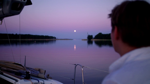 浪漫的湖上日落。从船上看风景的年轻人视频素材