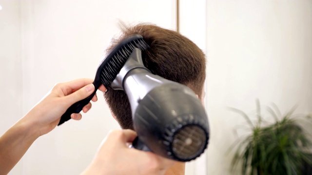 理发师在理发店里吹干头发，给他的头发吹干视频素材