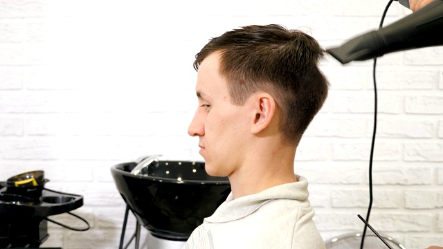 沙龙里的男性发型。理发师在理发店里吹头发。视频素材