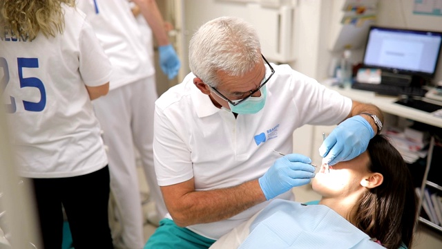 一个成熟的牙医在治疗一个年轻的女病人视频素材