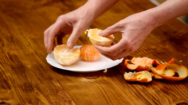 手剥柑橘类水果。健康食品。女性双手剥橘子。美味的橘子片水果。季节性的柑橘类水果。视频素材
