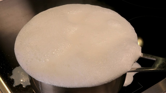 煮天然有机牛奶，在锅里煮牛奶，牛奶即将溢出，溢出牛奶视频素材