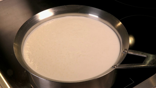 煮天然有机牛奶，在锅里煮牛奶，牛奶即将溢出，溢出牛奶视频素材