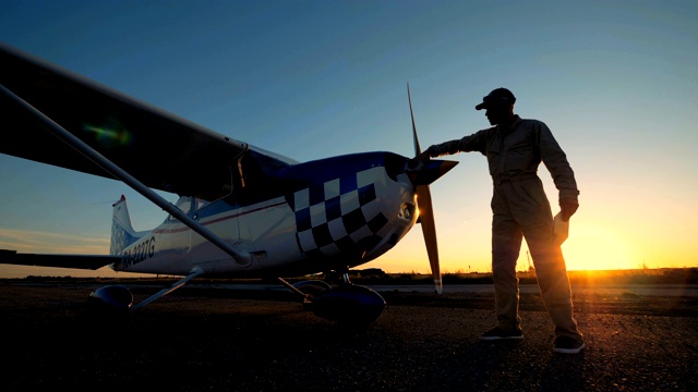 一名男性飞行员正在擦飞机的螺旋桨，侧视图。视频素材