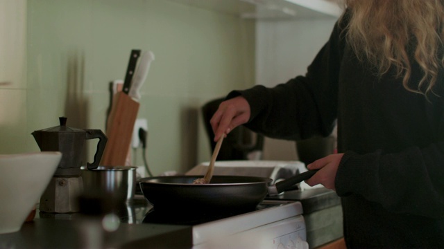 一个女人用木勺在煎锅里搅拌食物视频素材