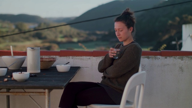 在屋顶露台上喝着热水吃早餐的女人视频素材