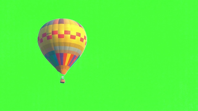 在壮观的白色天空和绿色屏幕或色度键背景下，从左到右，黄色彩色单一热气球在空中飞行的4K视频跟踪拍摄。视频购买