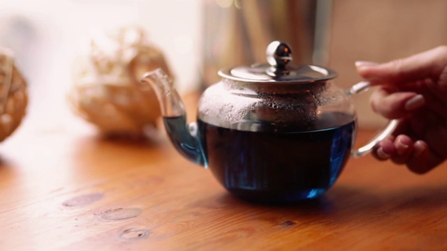蓝蝴蝶豌豆茶，从花阴蒂里亚在咖啡馆的桌上。一种花香，异国情调，蓝色泰国茶，有助于促进减肥。健康和排毒。视频素材