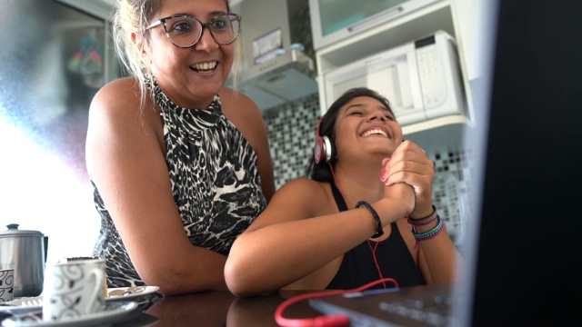 母亲和女儿在家里边听音乐边用笔记本电脑视频素材