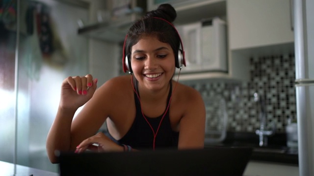 一个年轻的拉丁女人在家边听音乐边用笔记本电脑视频素材