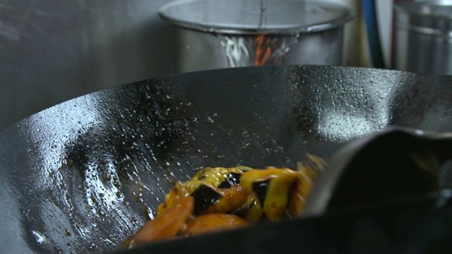 中国菜“地三鲜”(炒土豆、茄子和辣椒)在炒锅里炒视频下载