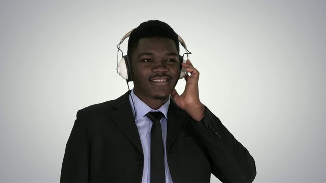 英俊的非洲裔美国商人戴着耳机在听渐变背景音乐视频素材