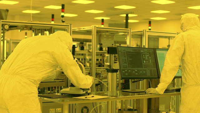 无菌高精密制造实验室，科学家在防护服使用计算机和显微镜，做药理学，生物技术和科学研究。橙色的颜色视频素材