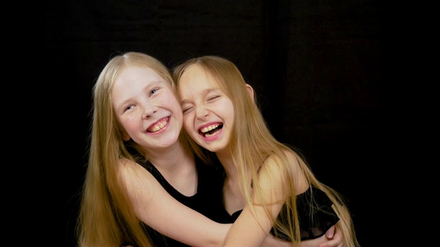 肖像拥抱美丽的年轻女孩朋友孤立地站在黑色的黑色背景切割微笑和大笑视频下载