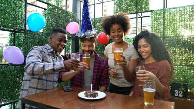 一群朋友在庆祝生日时，他吹灭了蜡烛，并提议喝啤酒视频素材
