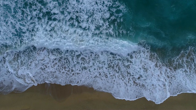 泡沫状的海浪翻滚着涌向沙滩。空中拍摄，4K视频素材