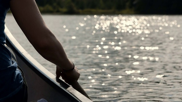 一名葡萄牙女子在日落时分在湖上划独木舟的视频。视频素材