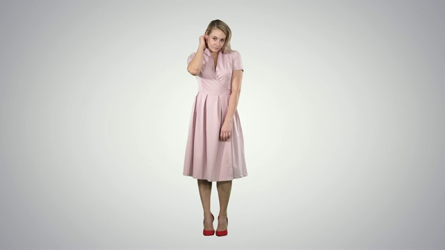 美丽温柔的女孩在粉红色的衣服看着镜子在梯度的背景视频下载