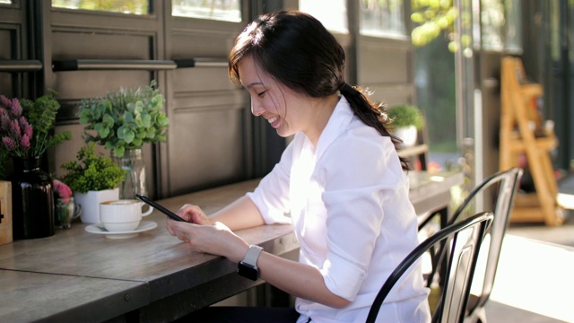 慢镜头年轻女子在咖啡馆使用手机视频素材